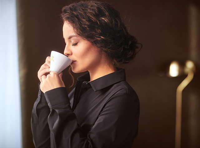 Person digging two hands into a pile of coffee beans and filling their palms with coffee beans and lifting them up